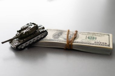Dolar banknotlarının arka planında oyuncak tankı.