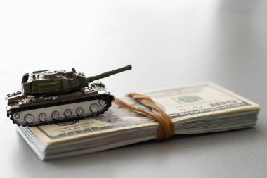 Dolar banknotlarının arka planında oyuncak tankı.
