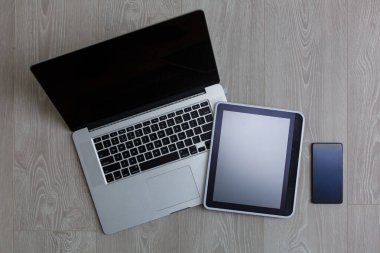 Modern dizüstü bilgisayar, cep telefonu ve Beyaz ahşap zemin üzerinde tablet