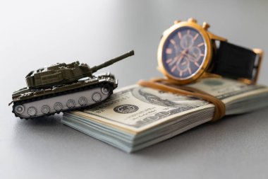Dolar banknotlarının arka planında oyuncak tankı