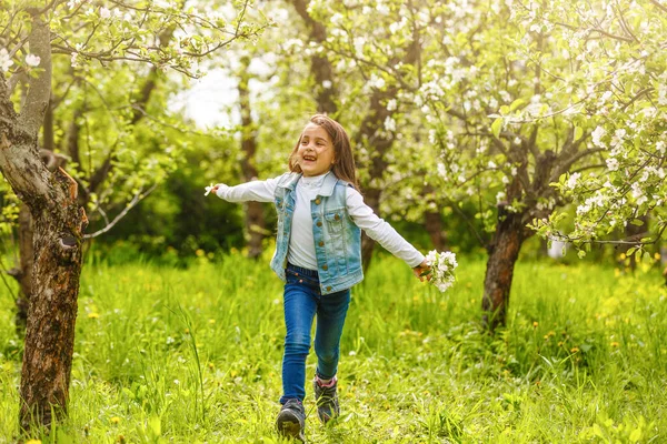 一个美丽的小女孩贯穿在春天的花园里开满 可爱的孩子在一个盛开的花园 在日落的金发 — 图库照片