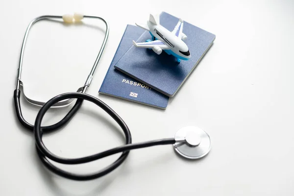 Medical Tourism, medical travel concept. Stethoscope, toy plane and passport on grey background