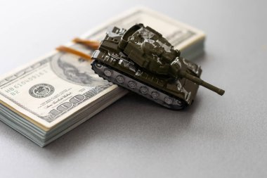 Dolar banknotlarının arka planında oyuncak tankı.