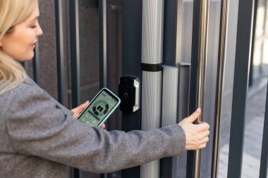 Akıllı ev kavramı - kadına yakın çekim - Elektronik kilit açmak için cep telefonu kullanın.