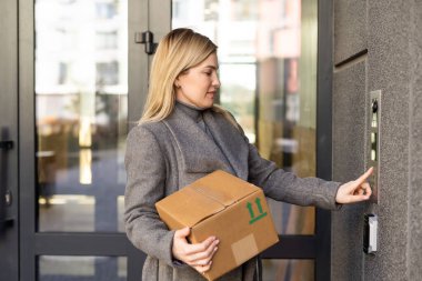 Bina girişinde dahili telefon kullanan kadın