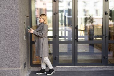 Akıllı ev kavramı - kadına yakın çekim - Elektronik kilit açmak için cep telefonu kullanın.
