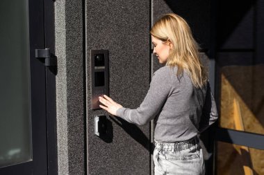 Bina girişinde dahili telefon kullanan kadın
