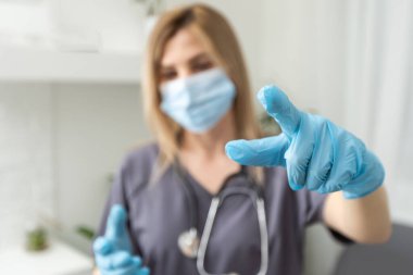 Kadın doktorlar elleri nitril içinde mavi eldivenler parmak gösteriyor..