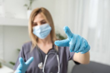 Lastik eldiven takan bir kadın doktor bir şey tuttuğunu gösteriyor.