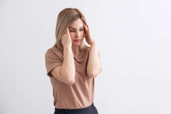 stock image Portrait of beautiful young touching her temples feeling stress, on gray background.