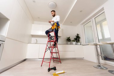 Apartmanın içine elektrik lambaları döşeyen elektrik işçisi. İnşaat dekorasyonu kavramı