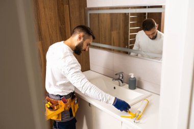 Professional plumber with plunger and instruments near sink