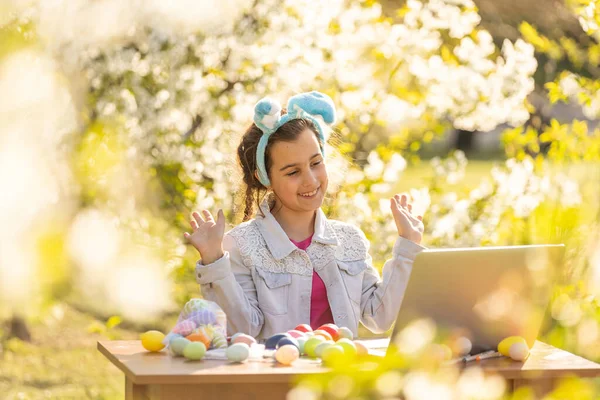 Fröhliche Teenie Mädchen Tragen Hasenohren Bemalt Ostereier Mit Laptop Garten — Stockfoto