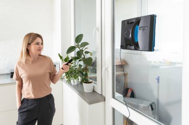 Yüksek bina açık havada elektrikli süpürge robot temizleme penceresi. genç kadın uzaktan kumanda