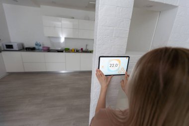 Oturma odasındaki duvara dijital dokunmatik ekran panelle evi kontrol etmek. Evdeki akıllı aygıtları yönetmek için akıllı ev ve mobil uygulama kavramı.