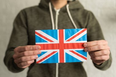 Hand holding flag of UK, isolated on white background.