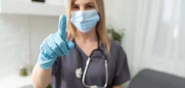 Kadın doktorlar elleri nitril içinde mavi eldivenler parmak gösteriyor..