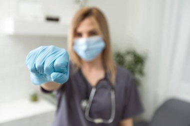 Tıp çalışanları, covid-19 salgını, koronavirüs konsepti. Üzgün ve hayal kırıklığına uğramış kadın doktor gergin görünüyor, baskı altında, bir şeyler bekliyor, kötü haberler alıyor, hoşnutsuzca yumruk sallıyor.