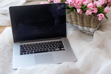 Table with laptop and flowers in a basket.