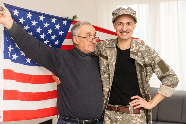 an elderly father and a military son saluting American flag.