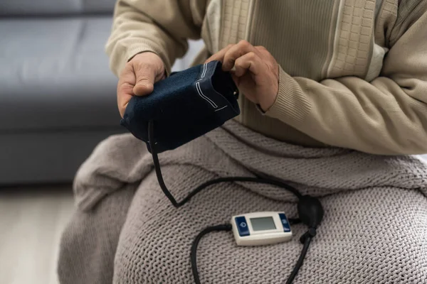Idősebb Férfi Otthoni Vérnyomásmérőt Használ Hogy Ellenőrizze Életjeleit Nappaliban Ülve — Stock Fotó