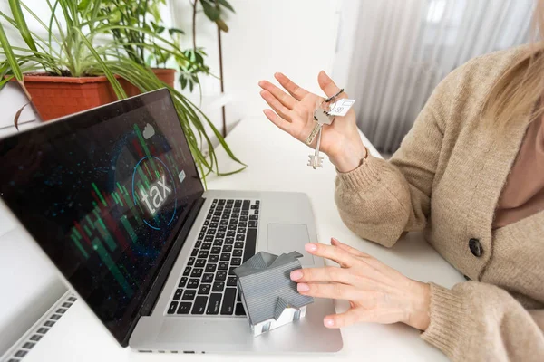 Woman holding keys with laptop and taxes