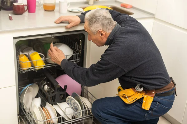 Man In Overall With Toolbox Repairing Dishwasher.