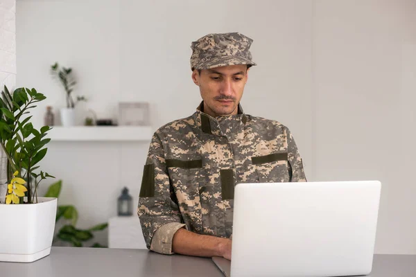 Surveillance and control of opposing information concept, Soldier in camouflage uniform working on laptop for Information Operation.