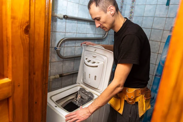 家電の修理を自分の手でやっています 修理工は洗濯機を修理する 家庭やワークショップでの家電修理のためのサービス — ストック写真