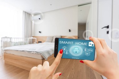 Akıllı ev telefonu, akıllı ev telefonu uygulama arayüzü cep telefonu ekranında, modern apartmandaki tüm ev sistemini telefonla kontrol eden genç bir kadın, konsept internet.