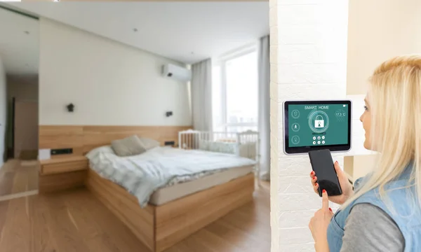 pretty blonde woman using smart home control panel .