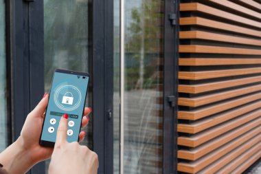 ekranda siyah mobil akıllı telefon akıllı evine uygulamasıyla tutan el. arka plan bulanık ev. Tüm ev denetimleri ve ev güvenlik bakımı için erişim.