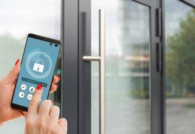ekranda siyah mobil akıllı telefon akıllı evine uygulamasıyla tutan el. arka plan bulanık ev. Tüm ev denetimleri ve ev güvenlik bakımı için erişim.