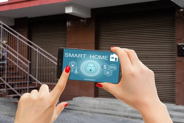 stock image Cropped image of female entering secret key code for getting access and passing building using application on mobile phone, woman pressing buttons on control panel for disarming smart home system.