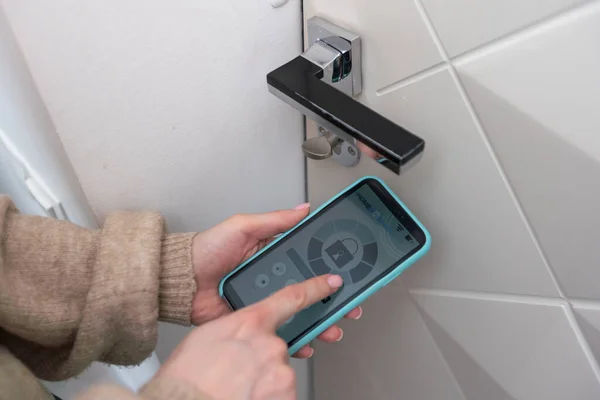 Woman hands using phone scan to digital door lock security systems at home.