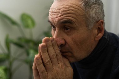 Lütfen, Tanrım. Endişeli, yaşlı, beyaz bir adam evdeki kanepede dua ediyor. Stresli beyaz Avrupa vatandaşı koltukta oturuyor, af diliyor ya da zor bir durumda Tanrı 'dan yardım diliyor.
