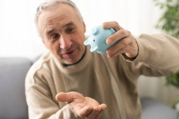 Senior caucasian man holding piggy bank with glasses depressed and worry for distress, crying angry and afraid. sad expression.