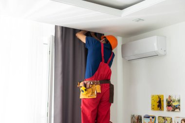 man doing house works, attach the railing and hang curtains at home