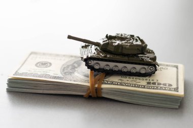 Dolar banknotlarının arka planında oyuncak tankı