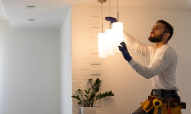 Elektrik işçisi yeni dairede lamba monte ediyor.