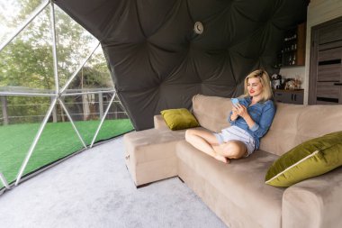 Evde dinlenirken akıllı telefon kullanan güzel bir kadının fotoğrafı..