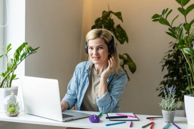 Laptop ekranına bakıp gülümseyen genç bir kadın, mesajda iyi haberler okuyor, video izliyor, sosyal ağda sohbet ediyor ya da evde online alışveriş yapıyor, bilgisayarla boş vakitlerin keyfini çıkarıyor.