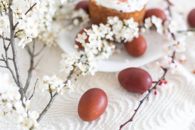 Paskalya pastası ve boyalı yumurta. Çiçek açan buket masanın yanında yatıyor.