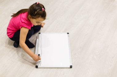 Genç sevimli küçük çocuk görüntüsü. Sınıftaki küçük kız. Çocuk okul tebeşir tahta yakınında duruyor. Kameraya bakıyorum. Okul konsepti.