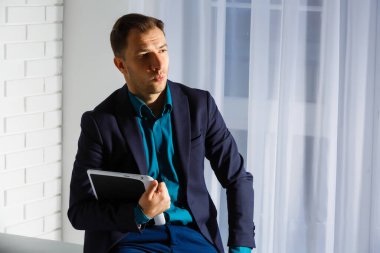 Boş ofislerdeki paketlerin yanında duran genç bir adamın portresi.