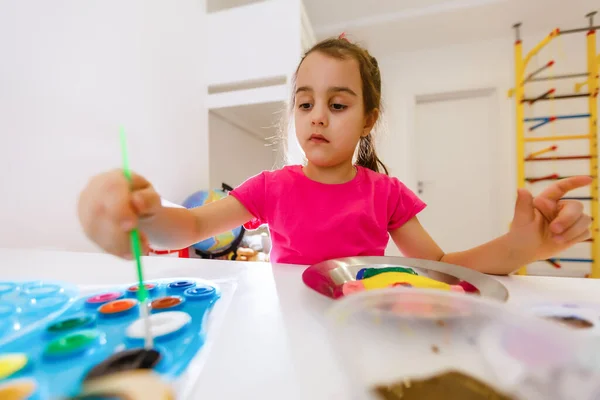Little girl painting in her nursery at home