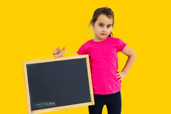 可爱的小女孩 拿着黑板 孤立的黄色背景 — 图库照片