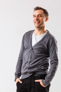 Sıradan bir yakışıklılık. Kollarını kavuşturup gülümseyen ve beyaz arka planda duran kendinden emin genç yakışıklı bir adam.