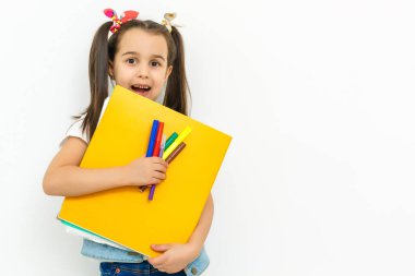 Okul kız çocuk sırt çantası ve beyaz bir arka plan üzerinde izole kitap ile gülümseyen portresi