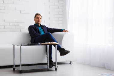 Beyaz arka planda beyaz bir kanepede genç bir işadamı